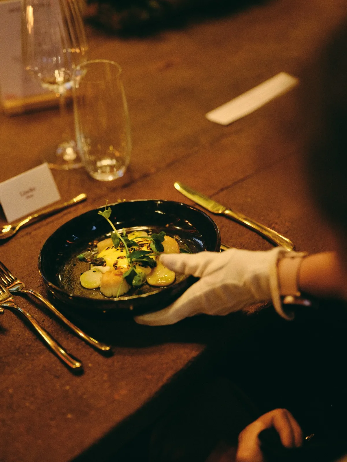 Verfijnd gerecht wordt met witte handschoenen aan tafel geserveerd, catering door HEAT