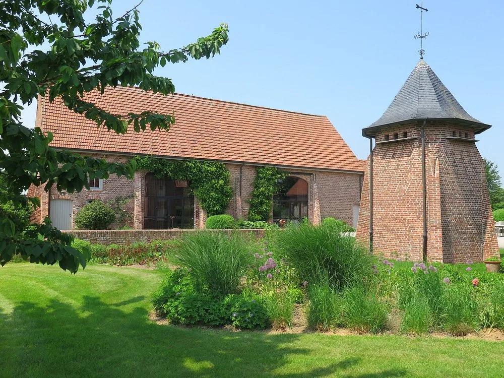 Authentieke hoeveschuur met begroeide gevel en duiventil aan de siertuin van Speghelhof